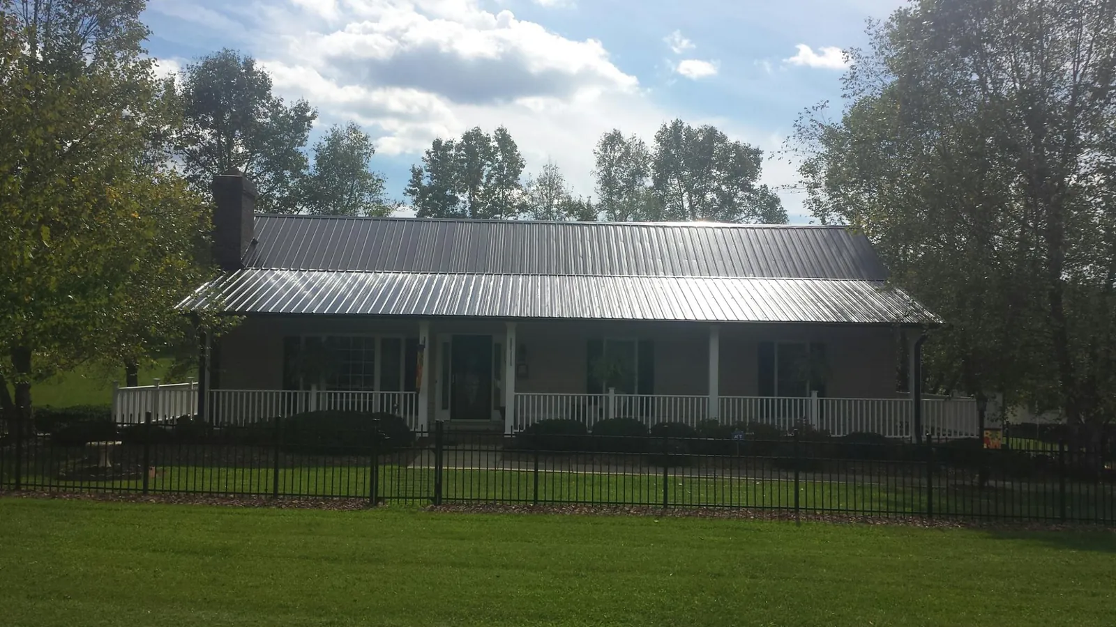 Gray metal roof on a brick ranch with a full width front porch — Gutter Guard Installation work by our crew in Clayton